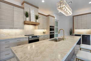 Kitchen with hanging light fixtures, a kitchen bar, stainless steel appliances, and a kitchen island with sink