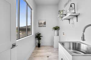 Washroom with sink, light hardwood / wood-style flooring, a healthy amount of sunlight, and washer hookup