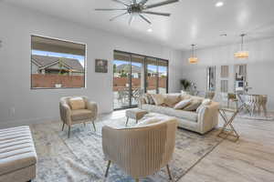 Living room with light wood-type flooring and ceiling fan with notable chandelier