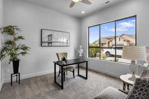 Carpeted office featuring ceiling fan