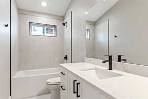 Full bathroom with toilet, tiled shower / bath combo, and vanity