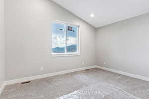 Unfurnished room with carpet flooring and vaulted ceiling