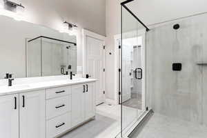 Bathroom with tile patterned floors, double sink vanity, and a shower with door