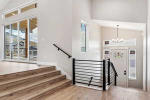 Foyer with a notable chandelier, high vaulted ceiling, and hardwood / wood-style floors