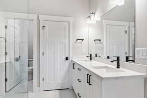 Bathroom featuring toilet, dual bowl vanity, and tile patterned floors