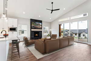 Living room with a premium fireplace, light wood-type flooring, sink, and ceiling fan