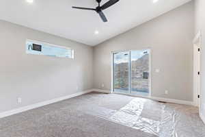 Carpeted empty room with lofted ceiling, ceiling fan, and a healthy amount of sunlight