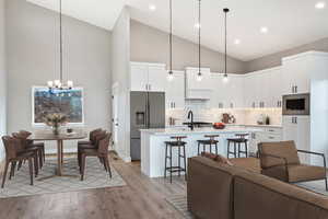 Living room featuring sink, high vaulted ceiling, a notable chandelier, and light hardwood / wood-style floors