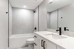 Full bathroom featuring tiled shower / bath combo, vanity, and toilet