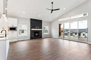 Unfurnished living room featuring hardwood / wood-style floors, sink, a premium fireplace, and ceiling fan