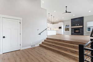 Living room featuring ceiling fan, light hardwood / wood-style flooring, a fireplace, and sink