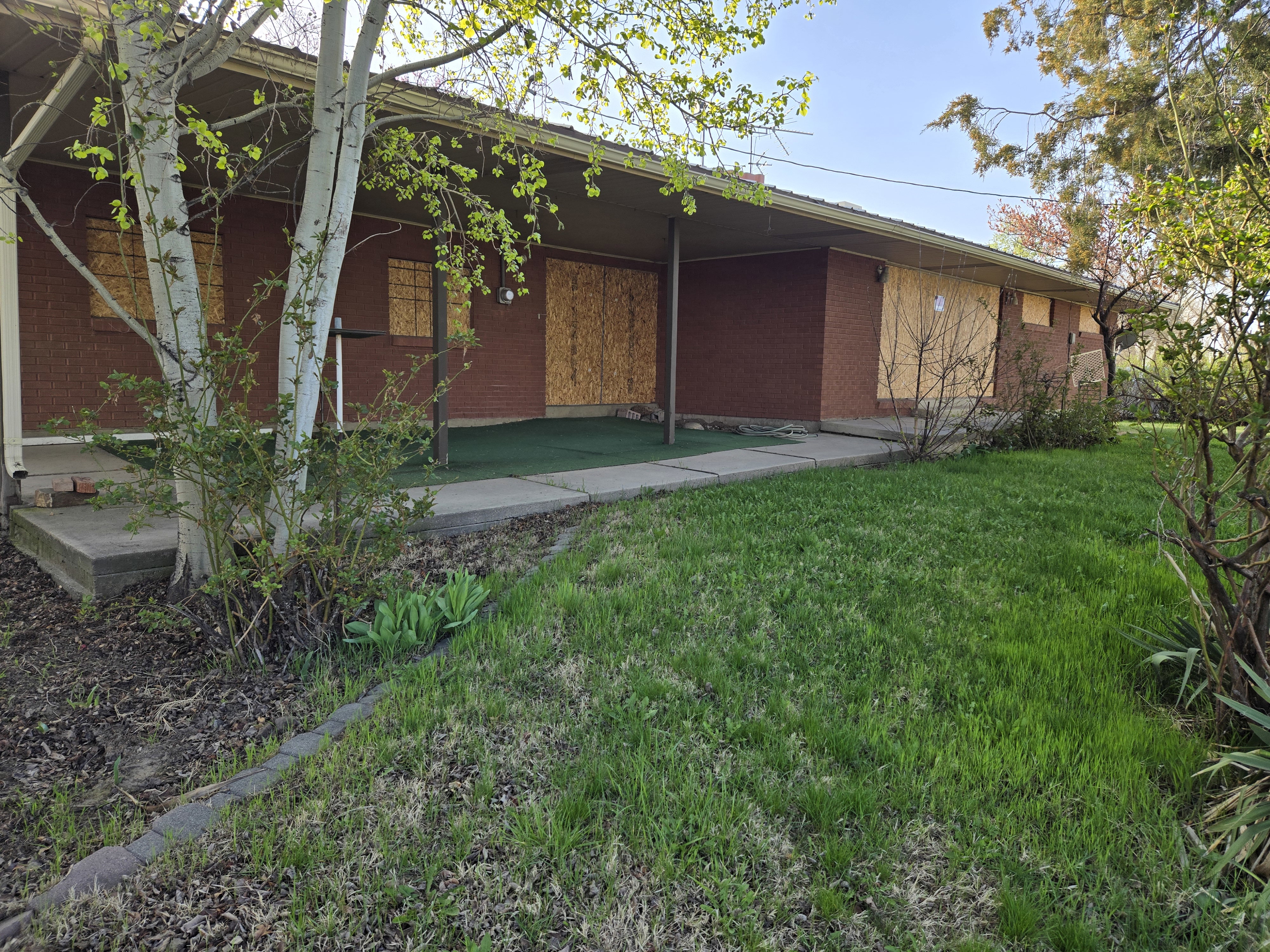 View of side of home featuring brick siding and a lawn