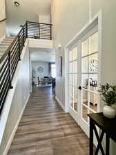 Hallway with a towering ceiling, french doors, and hardwood / wood-style floors