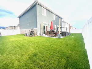 Rear view of house with a patio, cooling unit, and a lawn