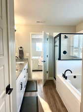 Bathroom with hardwood / wood-style floors, vanity, and shower with separate bathtub