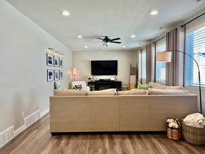 Living room with ceiling fan, a textured ceiling, a healthy amount of sunlight, and hardwood / wood-style flooring