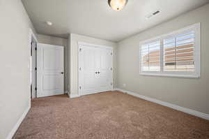 Bedroom 2 featuring light carpet, window, and a closet