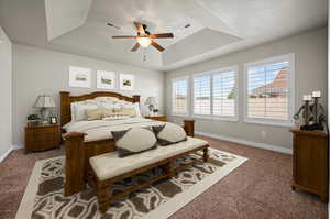 Virtual Carpeted primary bedroom with a tray ceiling, ceiling fan, and multiple windows