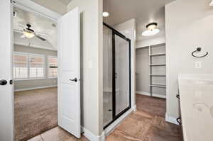 Primary connecting Bathroom with ceiling fan, sink, a shower with door, tile patterned flooring, double doors for wheelchair access, large walk-in closet with sky light