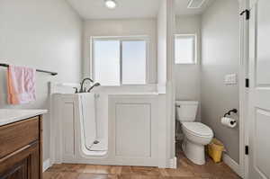 Primary Bathroom featuring tile patterned flooring, toilet, vanity, separate walk-in tub, and a healthy amount of sunlight