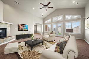 Virtual Carpeted Great room featuring ceiling fan, a tiled fireplace, high vaulted ceiling, walkout to patio in fenced yard, and a healthy amount of sunlight