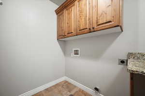 Laundry room with hookup for an electric or gas dryer, cabinets, light tile patterned flooring, and hookup for a washing machine