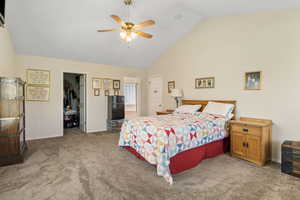 Carpeted bedroom featuring high vaulted ceiling, black refrigerator, a walk in closet, a closet, and ceiling fan