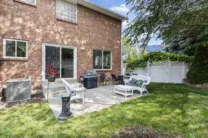 Rear view of property with central AC, a lawn, and a patio