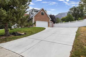 Exterior space with a garage, a mountain view, and a front lawn