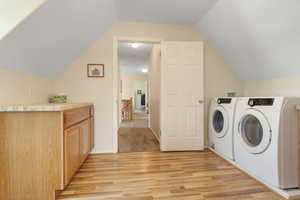 Washroom with light carpet, cabinets, and independent washer and dryer