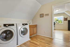 Laundry room featuring light hardwood / wood-style flooring, washing machine and dryer, cabinets, and sink