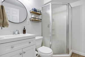 Bathroom with vanity, toilet, walk in shower, and hardwood / wood-style floors