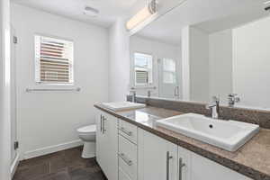 Bathroom with double vanity, toilet, and tile patterned flooring