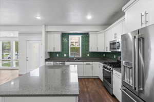 Kitchen with white cabinets, dark wood-type flooring, stainless steel appliances, and sink