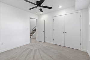 Unfurnished bedroom featuring ceiling fan, light carpet, and a closet