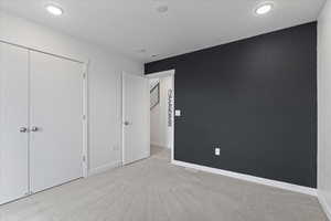 Unfurnished bedroom with light carpet and a closet