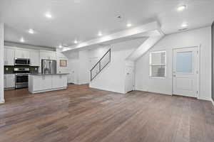 Kitchen with a kitchen island with sink, stainless steel appliances, hardwood / wood-style flooring, and white cabinetry