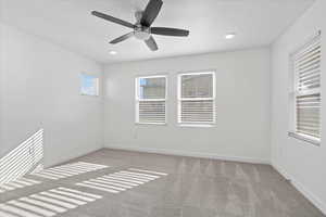 Carpeted spare room featuring ceiling fan