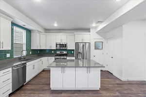 Kitchen with sink, stainless steel appliances, dark wood-type flooring, and a center island