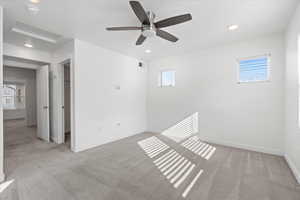 Carpeted spare room with ceiling fan and plenty of natural light