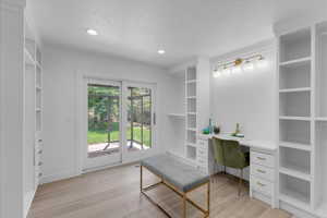 Office area featuring built in desk, light hardwood / wood-style flooring, and a healthy amount of sunlight