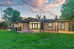 Back house at dusk featuring french doors and a yard