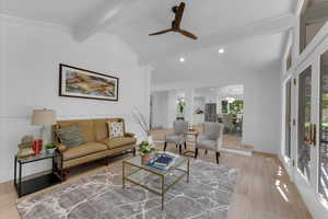 Living room with vaulted ceiling with beams, light wood-type flooring, ceiling fan, and a wealth of natural light