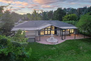 Back house at dusk with a patio and a yard