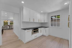 Kitchen with white cabinets, light wood-type flooring, stainless steel oven, and an inviting chandelier