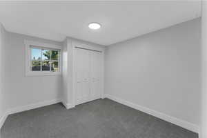 Unfurnished bedroom with dark carpet and a closet