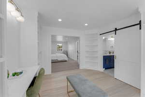 Bedroom featuring light carpet, a barn door, and ensuite bathroom