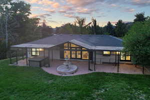 Back house at dusk with a patio area and a yard