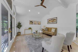 Living room with lofted ceiling with beams, light wood-type flooring, ornamental molding, and ceiling fan