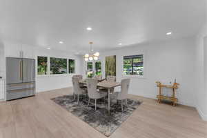 Dining space with light hardwood / wood-style flooring, a wealth of natural light, and an inviting chandelier